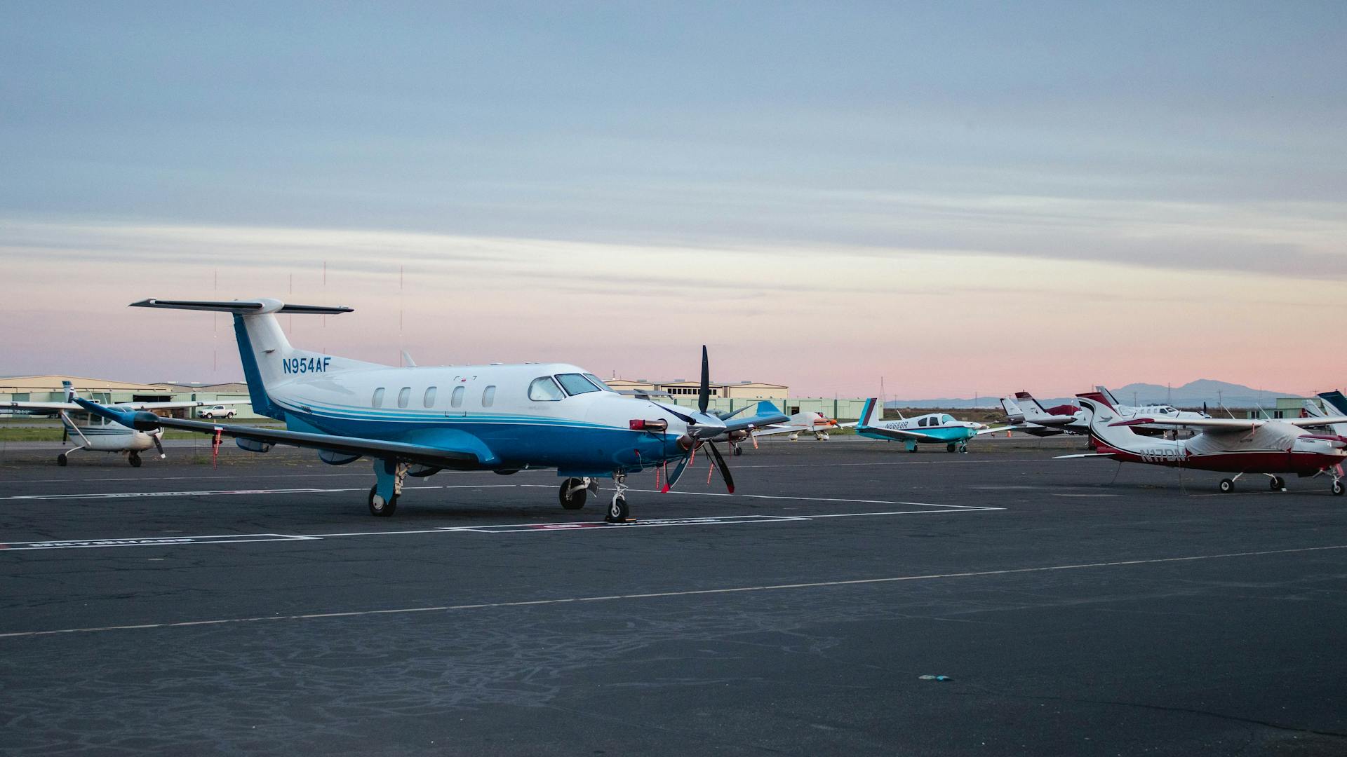 Row of private jets lined up on an FBO ramp at twilight