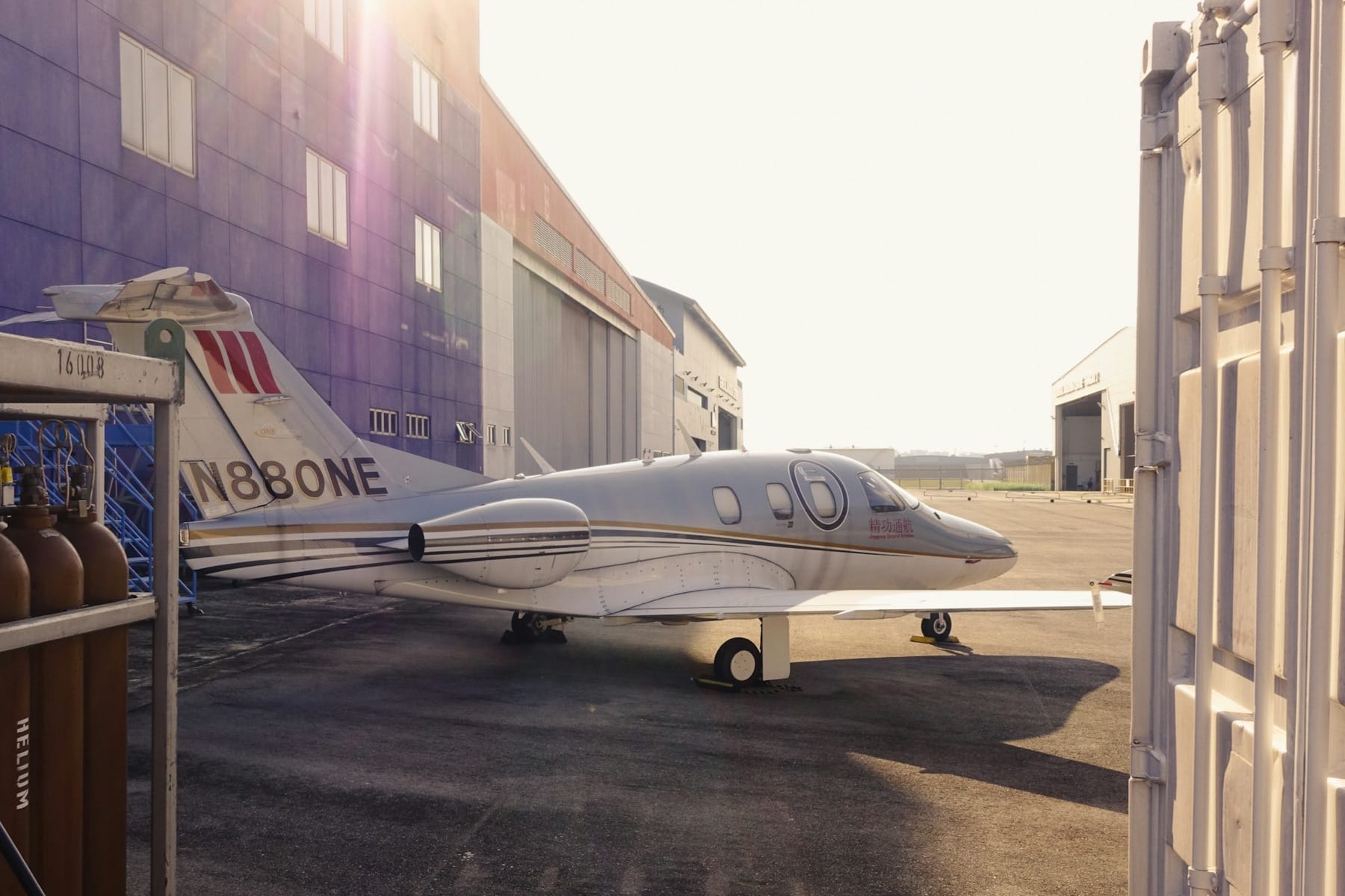 Business jet parked outside a line of hangars in low evening sun